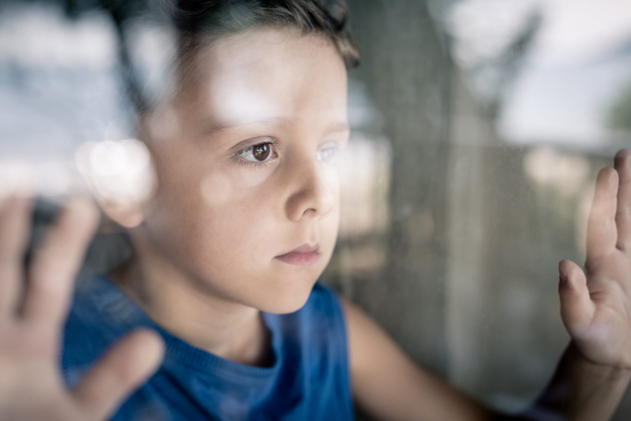 worried child looking out of a window